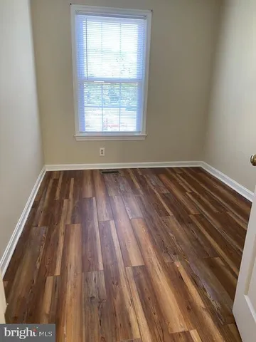 a view of a hallway with wooden floor and a bathroom