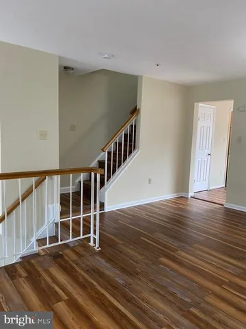 a view of an empty room with wooden floor and stairs