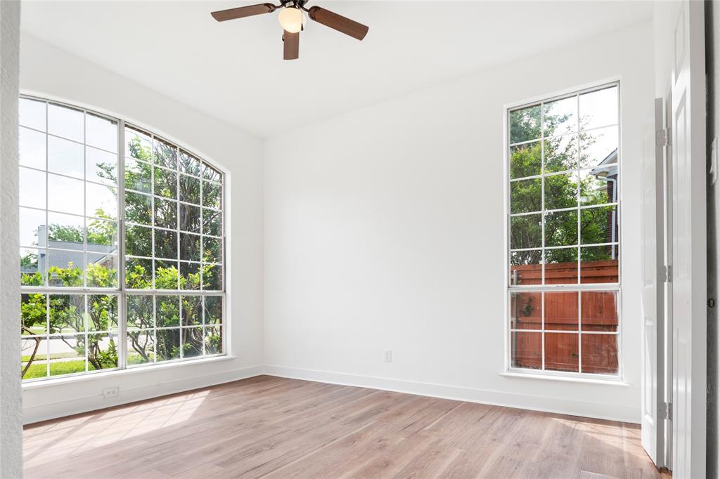 559 Raintree Circle Coppell, TX 75019 - Photo 19 of 40 Light-filled room featuring wood-finish flooring, a large arched window with grid panes, a second tall window with grid panes, a ceiling fan with light fixture, and white painted walls