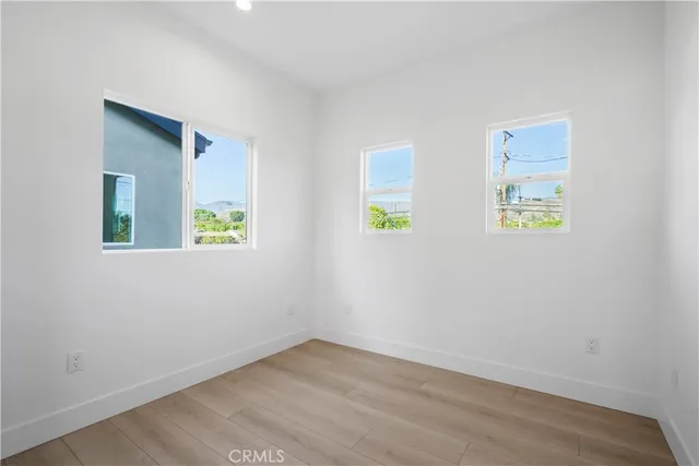 a view of an empty room with window and wooden floor
