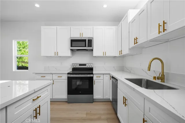 a kitchen with stainless steel appliances granite countertop a sink a stove a microwave and cabinets