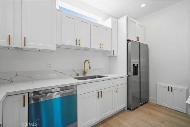 a kitchen with stainless steel appliances a sink cabinets and a wooden floor