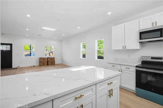 a kitchen with kitchen island granite countertop stainless steel appliances stove sink and cabinets