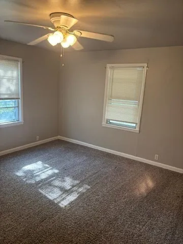 an empty room with windows and fan