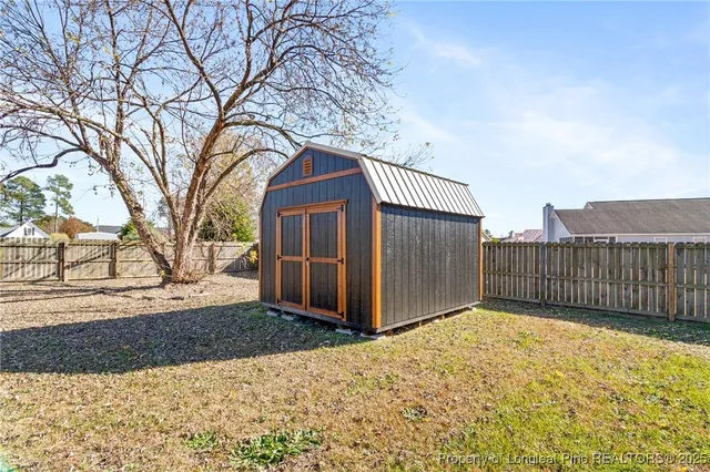 a view of a house with a large tree and wooden fence