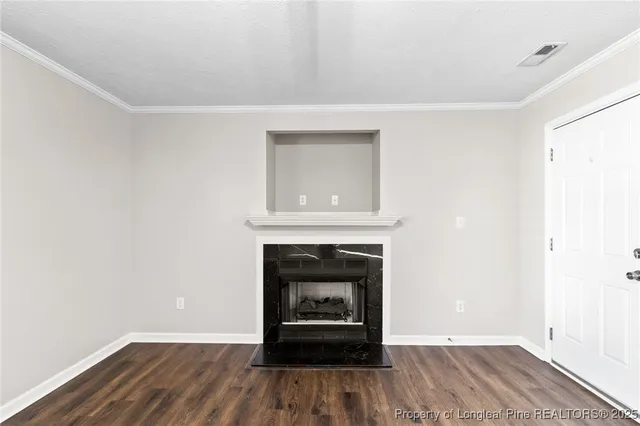a view of an empty room with wooden floor a fireplace and a window