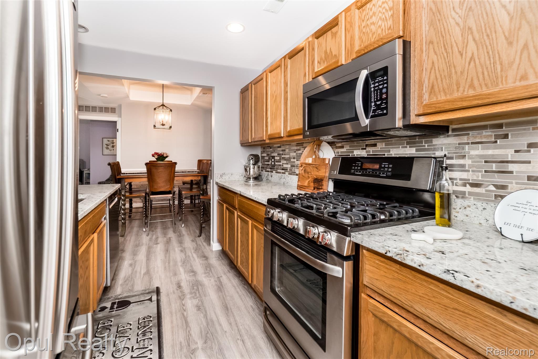 11762 Farmington Road Livonia, MI 48150 - Photo 10 of 25 Kitchen with stainless steel appliances, light stone countertops, hanging light fixtures, and light wood-style floors