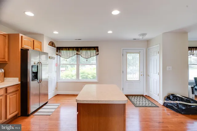 a large kitchen with stainless steel appliances granite countertop a stove a sink a refrigerator a center island and a window