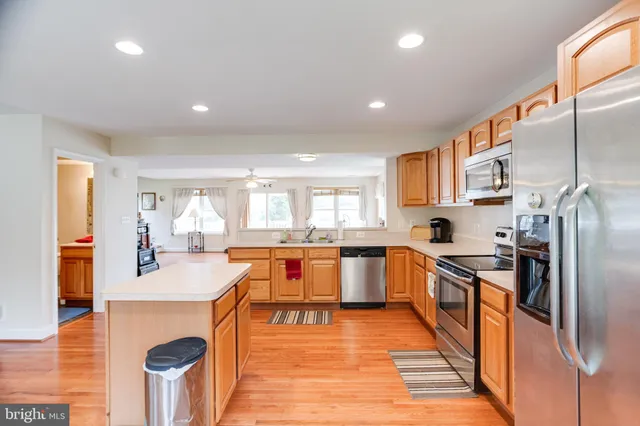 a open kitchen with stainless steel appliances granite countertop a refrigerator a stove and a wooden floors