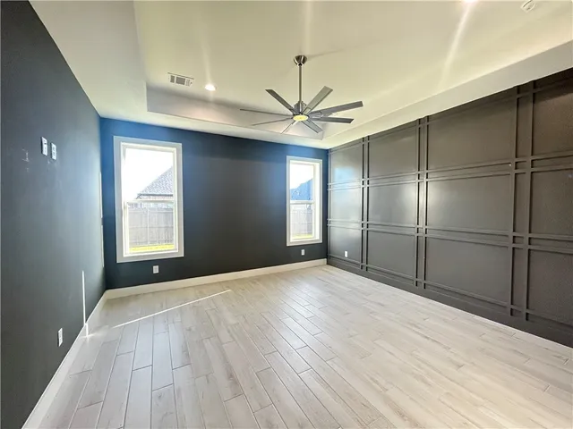 a view of empty room with wooden floor and fan