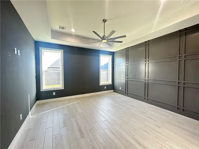 a view of empty room with wooden floor and fan