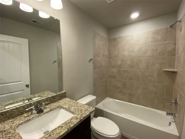 a bathroom with a granite countertop sink toilet mirror and bathtub
