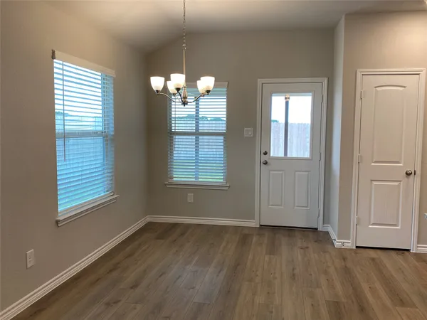 an empty room with wooden floor closet and windows