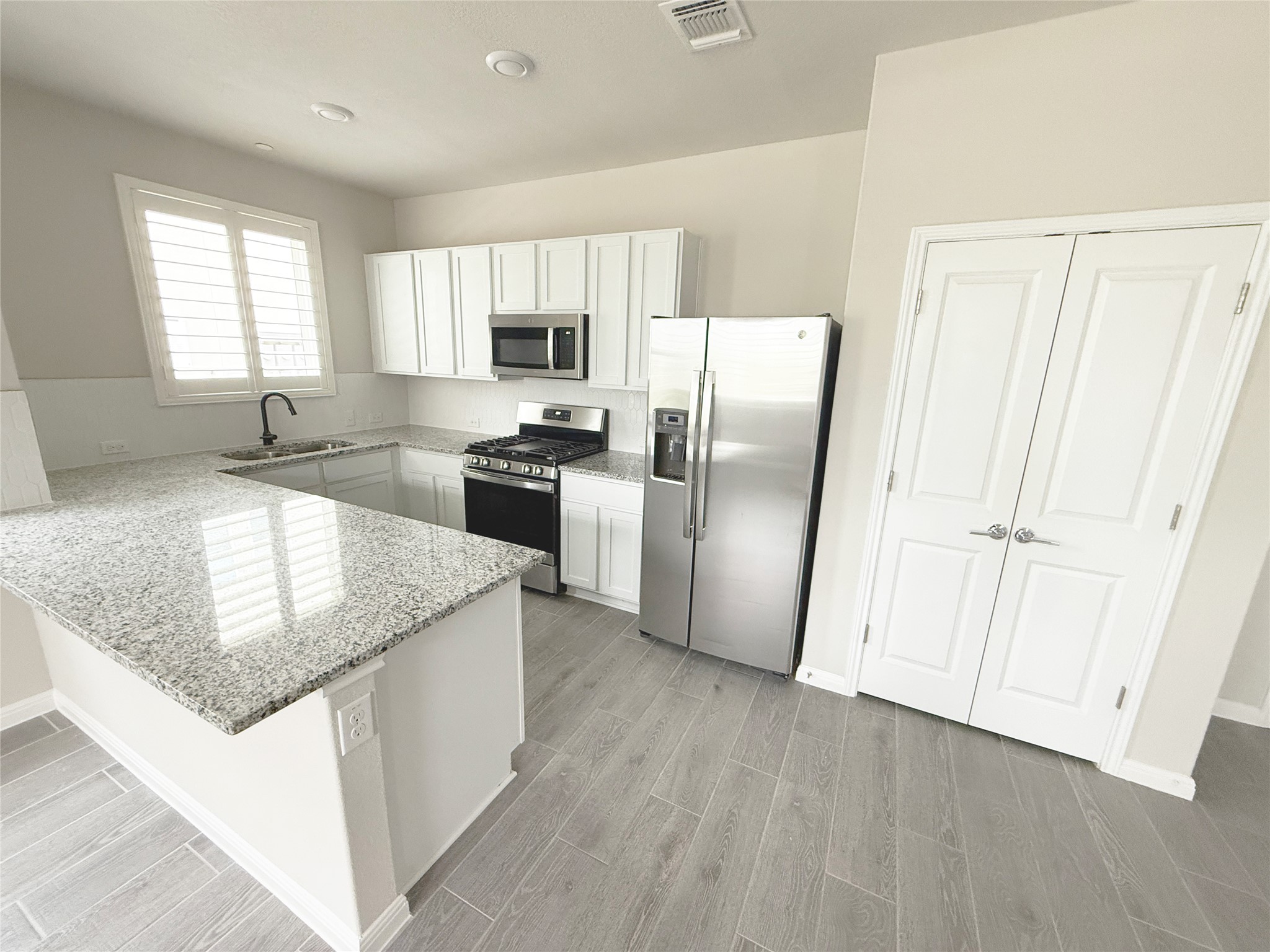9015 Cattle Baron Path, Unit 605 Austin, TX 78747 - Photo 2 of 20 Kitchen featuring visible vents, a sink, a peninsula, light wood-style flooring, and appliances with stainless steel finishes
