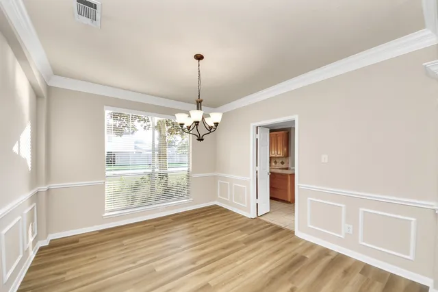 a view of an empty room with wooden floor a ceiling fan and windows