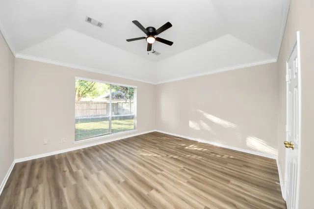 a view of a livingroom with wooden floor a ceiling fan and windows