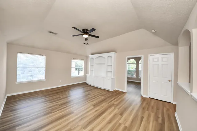 a view of empty room with wooden floor and fan