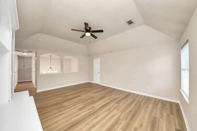 a view of an empty room with a window and wooden floor