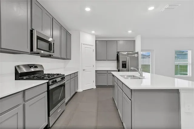 a kitchen with stainless steel appliances granite countertop a stove top oven a refrigerator a sink and dishwasher with wooden cabinet