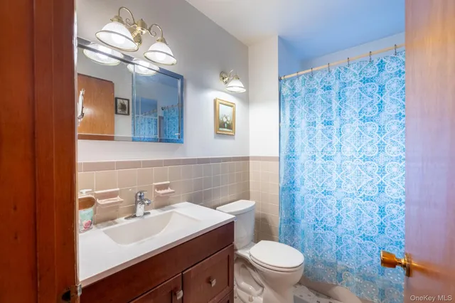 a bathroom with a toilet a sink a light fixture and a mirror