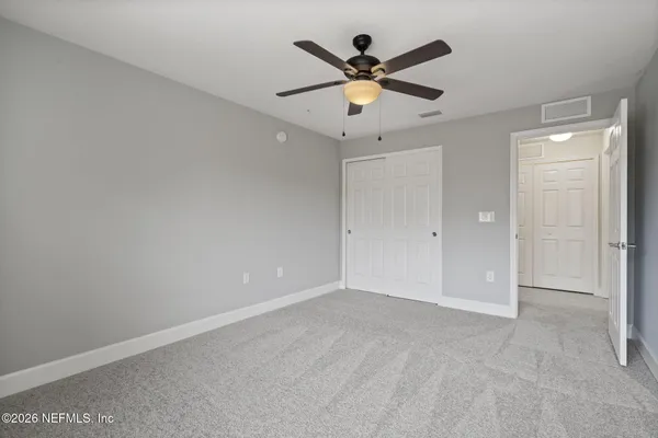 an empty room with chandelier fan and windows