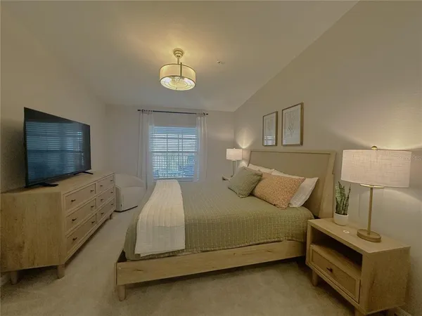 a bedroom with a bed and a flat tv screen on dresser