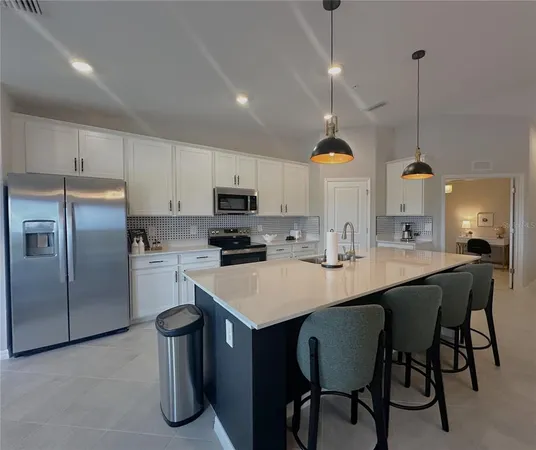 a kitchen with stainless steel appliances granite countertop a sink a stove a refrigerator and chairs