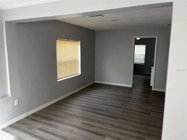 a view of an empty room with wooden floor and a window