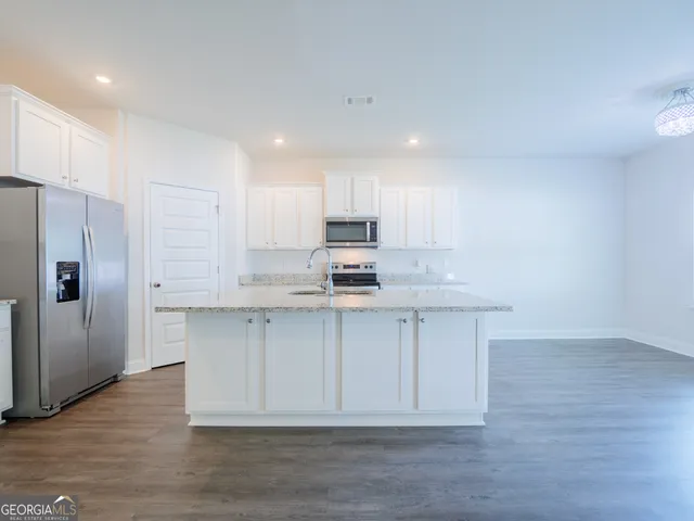 a kitchen with stainless steel appliances a refrigerator sink and white cabinets
