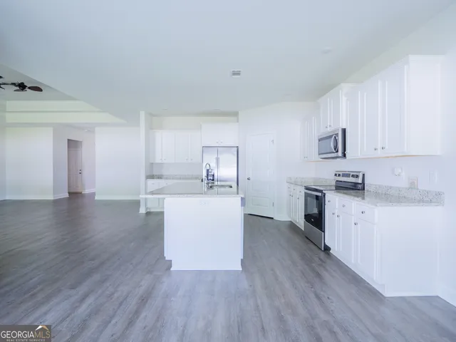 a kitchen with granite countertop a sink dishwasher stove and cabinets