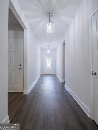 an empty room with wooden floor chandelier and windows