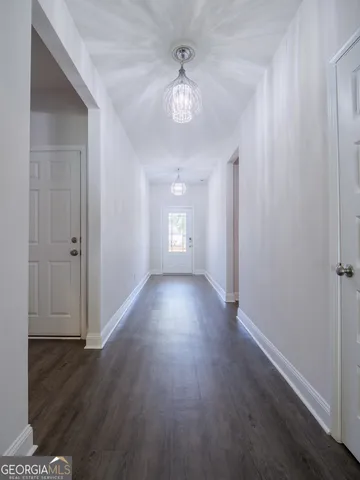an empty room with wooden floor chandelier and windows