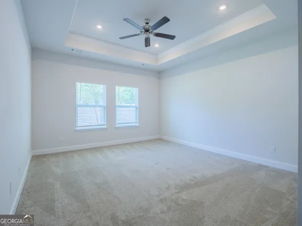 an empty room with a ceiling fan and carpet