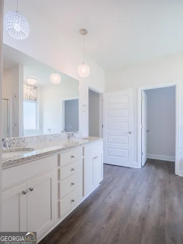 a bathroom with a granite countertop double vanity sink and mirror