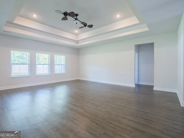a view of an empty room with a kitchen and wooden floor