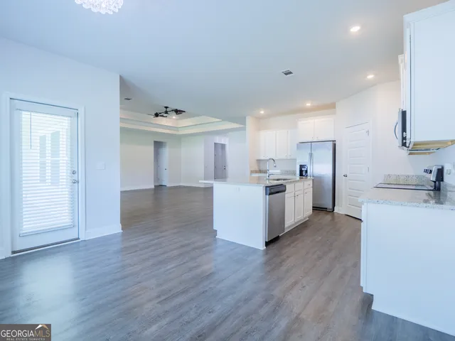 a kitchen with stainless steel appliances a stove top oven a sink white cabinets and wooden floor