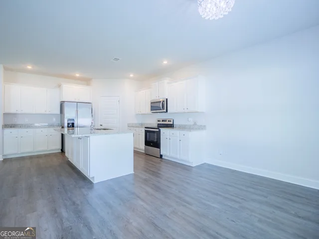 a kitchen with granite countertop a stove a sink and a refrigerator