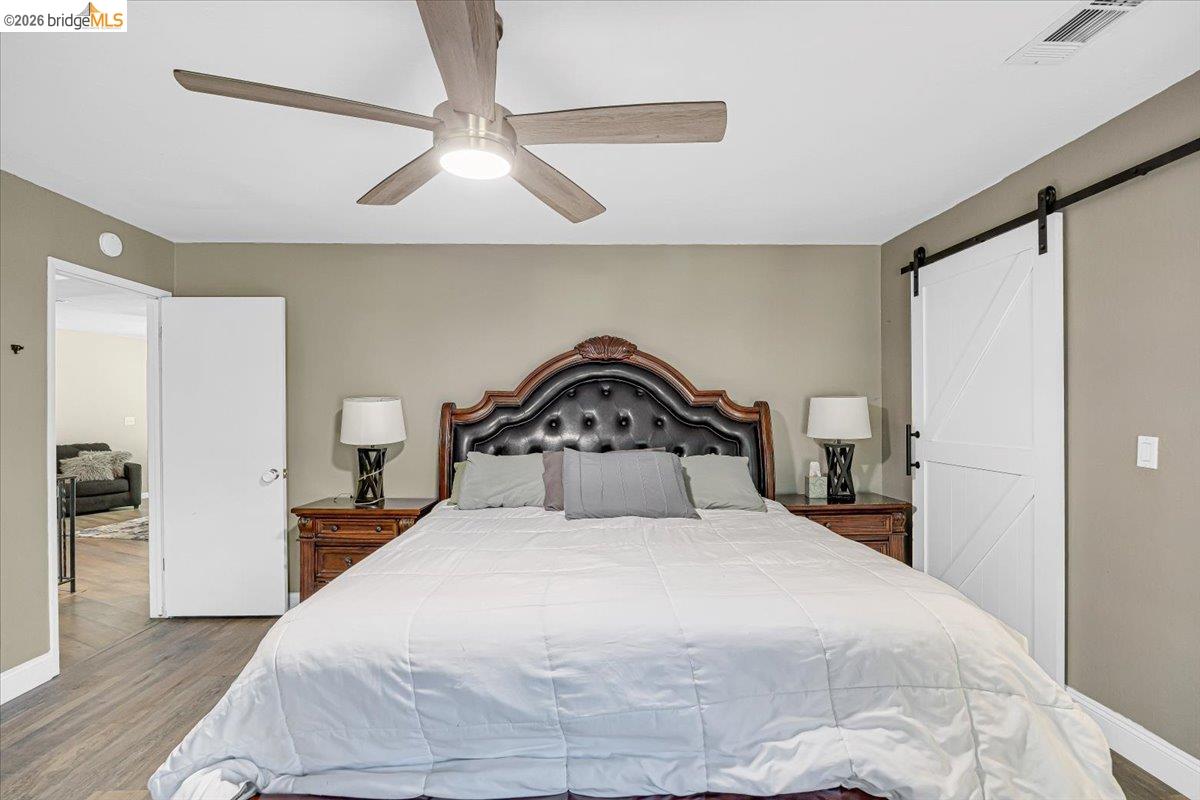 8733 Fraguero Road Sonora, CA 95370 - Photo 42 of 73 Neutral-toned room featuring wood-finish flooring, a ceiling fan with integrated lighting, and a white barn door on a black rail