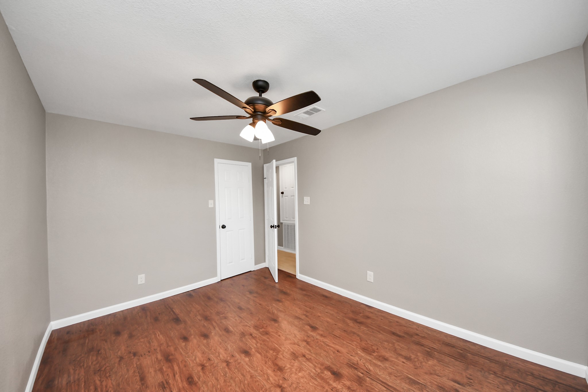 8918 Vinearbor Street Houston, TX 77033 - Photo 25 of 35 a view of a big room with wooden floor and a ceiling fan