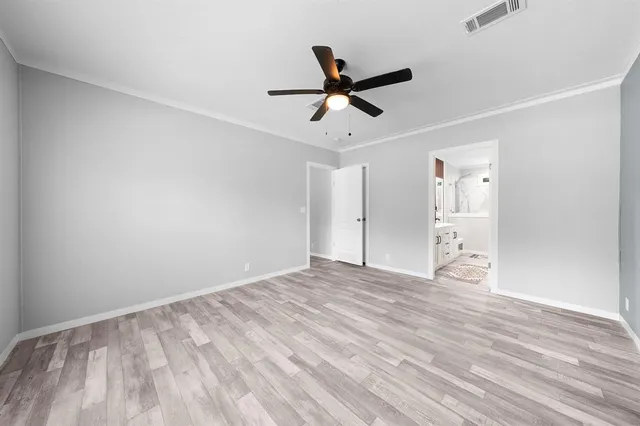 a view of empty room with wooden floor and ceiling fan