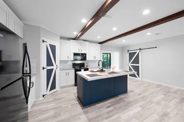 a kitchen with kitchen island stainless steel appliances a sink stove refrigerator and cabinets