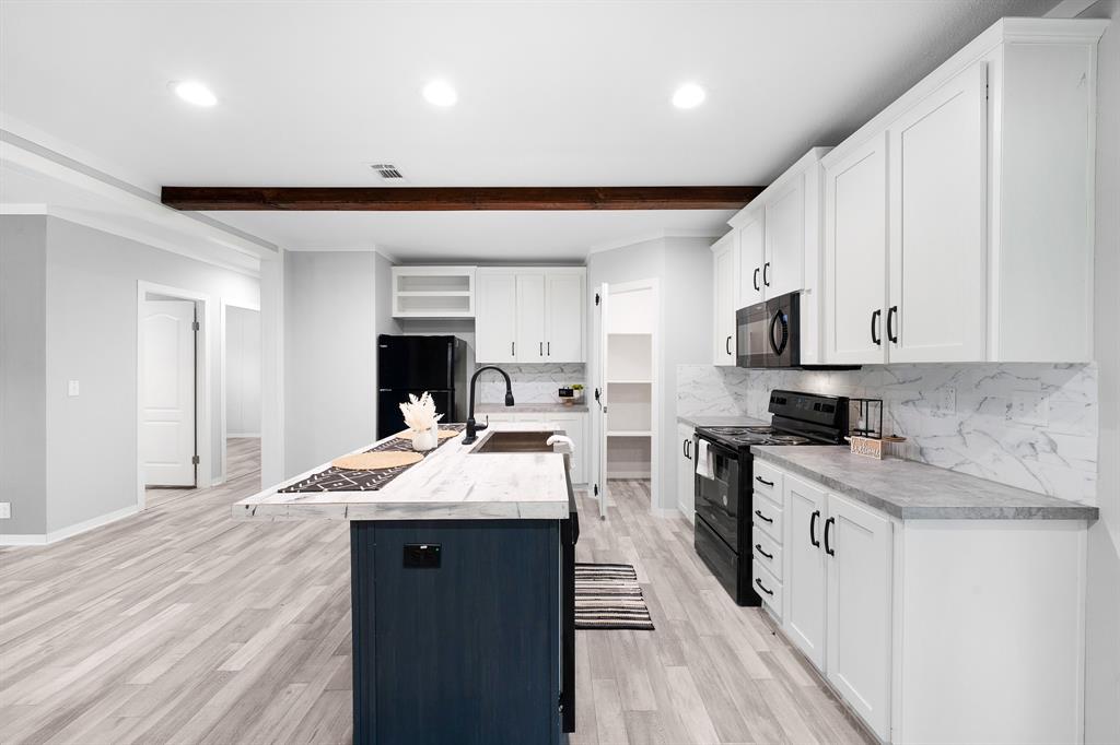 211 3900th Road Gilmer, TX 75644 - Photo 6 of 30 a open kitchen with kitchen island a sink stove and white cabinets