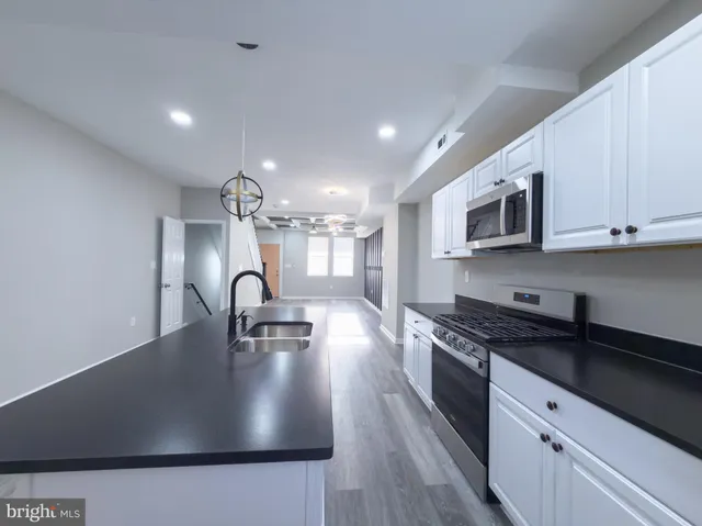 a kitchen with kitchen island granite countertop a sink a stove and cabinets