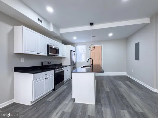 a large kitchen with stainless steel appliances granite countertop a stove a sink and a refrigerator