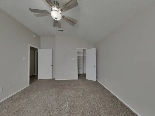 an empty room with closet and a chandelier fan