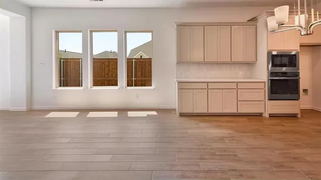 a view of an empty room with a kitchen and a window