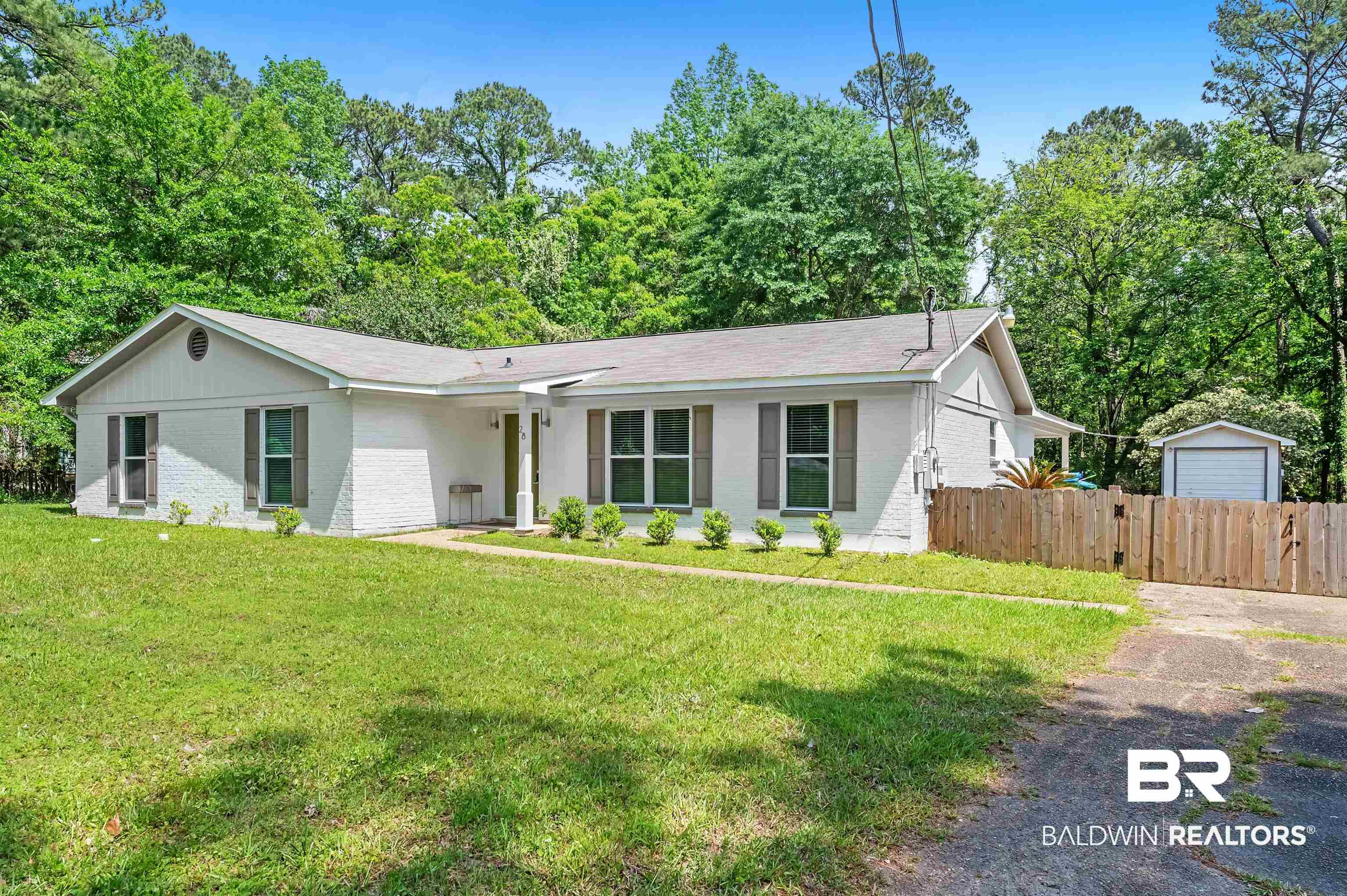 Ranch-style home featuring brick siding, fence, aphalt driveway, roof with shingles, and a front yard