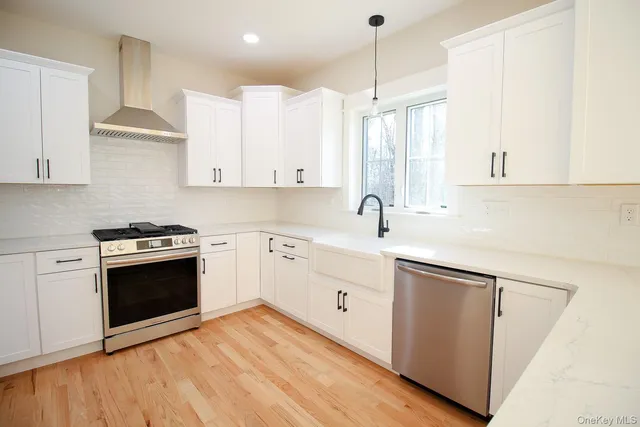 a kitchen with stainless steel appliances sink a stove and white cabinets