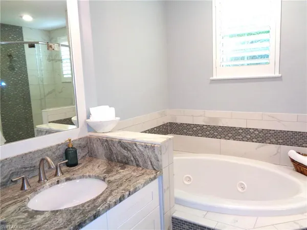 a bathroom with a granite countertop sink a mirror and a bathtub