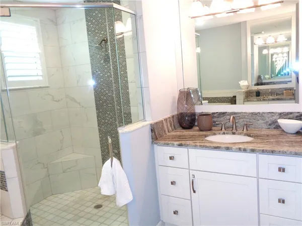 a bathroom with a granite countertop sink a mirror and shower